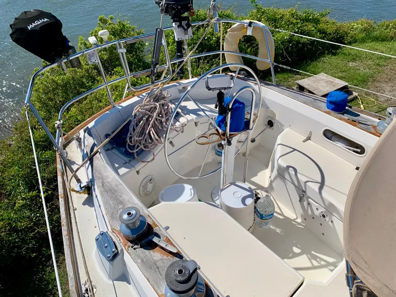 Slide: The Image of Cockpit of 1986 Sabre 36 sailboat with steering wheel and ropes, docked by water. - 13