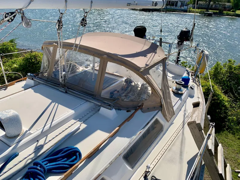 Slide: The Image of 1986 Sabre 36 sailboat with tan canopy, docked by a scenic waterfront. - 15