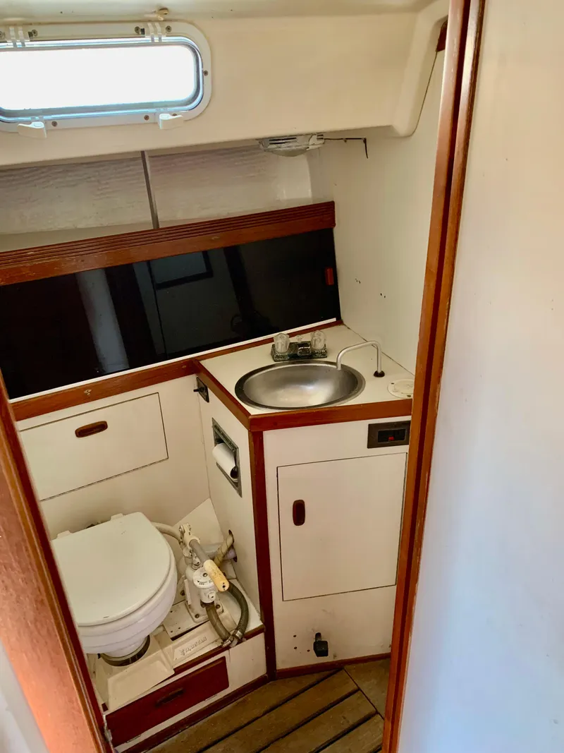 Slide: The Image of Compact bathroom in 1986 Sabre 36 sailboat with sink, toilet, and wooden accents. - 26