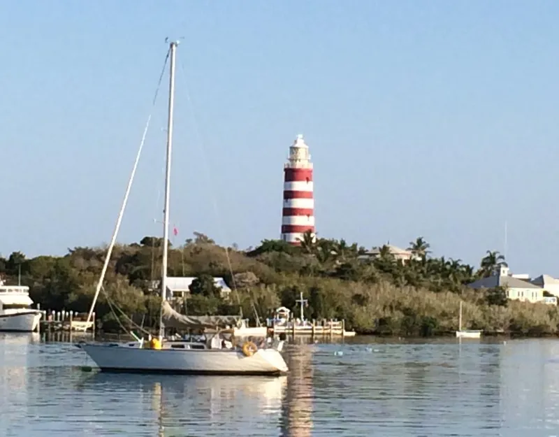 Slide: The Image of Sailboat Sabre 36 (1986) near striped lighthouse on calm water. - 58