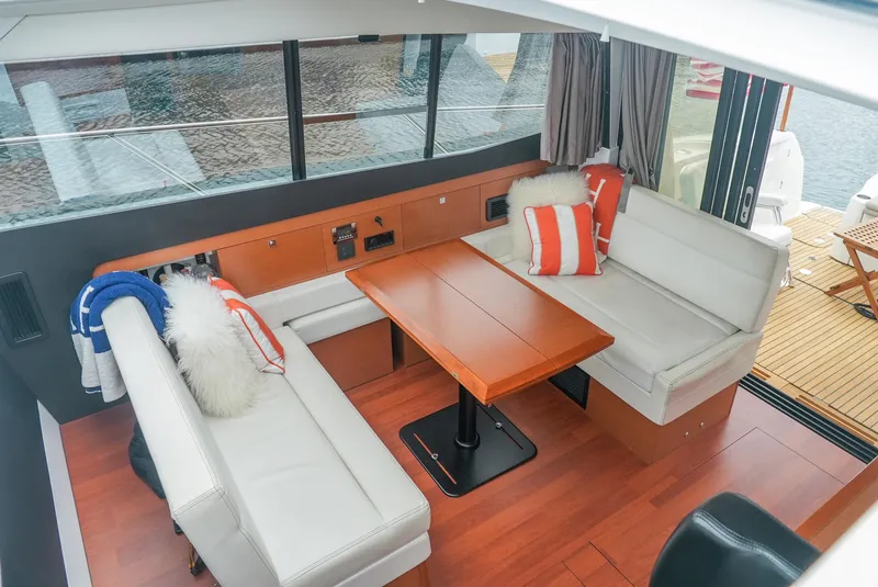 Slide: The Image of 2017 Jeanneau NC11 interior with cozy seating, wooden table, and nautical decor. - 18