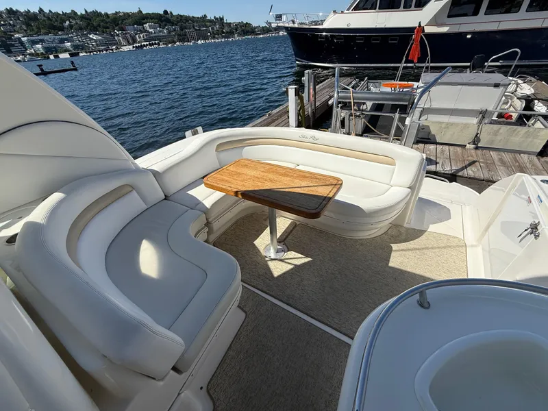 Slide: The Image of 2008 Sea Ray 340 Sundancer yacht with elegant seating and wooden table, docked by the water. - 10