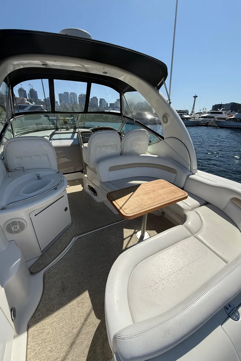 Slide: The Image of 2008 Sea Ray 340 Sundancer interior with seating and table, docked by the waterfront. - 12