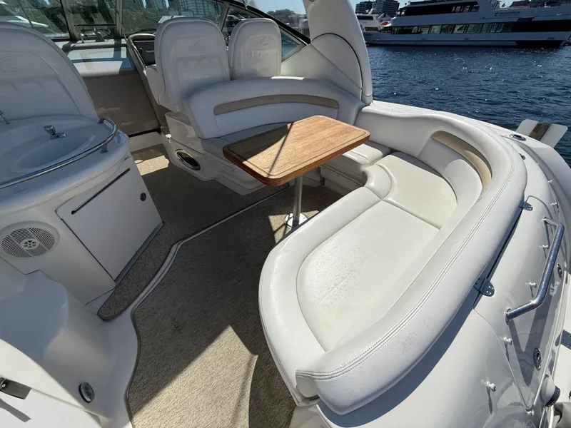 Slide: The Image of 2008 Sea Ray 340 Sundancer interior with white seating and wooden table, docked by the water. - 13