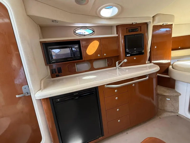 Slide: The Image of 2008 Sea Ray 340 Sundancer interior with kitchenette, featuring wood cabinetry and modern appliances. - 25