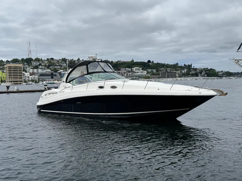 Slide: The Image of 2008 Sea Ray 340 Sundancer yacht on calm water, overcast sky, urban backdrop. - 4