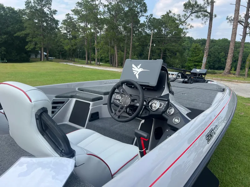 Slide: The Image of 2025 Skeeter ZXR 20 boat interior with modern dashboard and seating, set in a lush outdoor environment. - 5