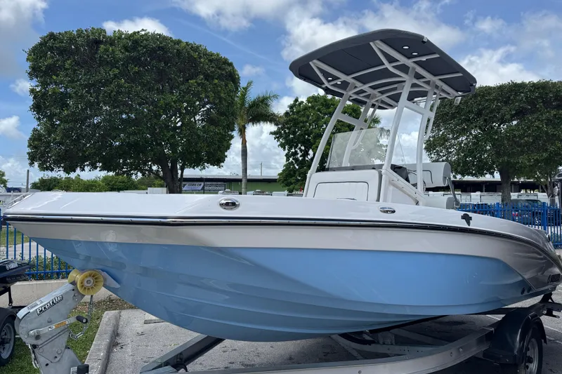 Slide: The Image of 2025 Yamaha Boats 195 FSH Sport, sleek design, light blue hull, parked outdoors. - 1