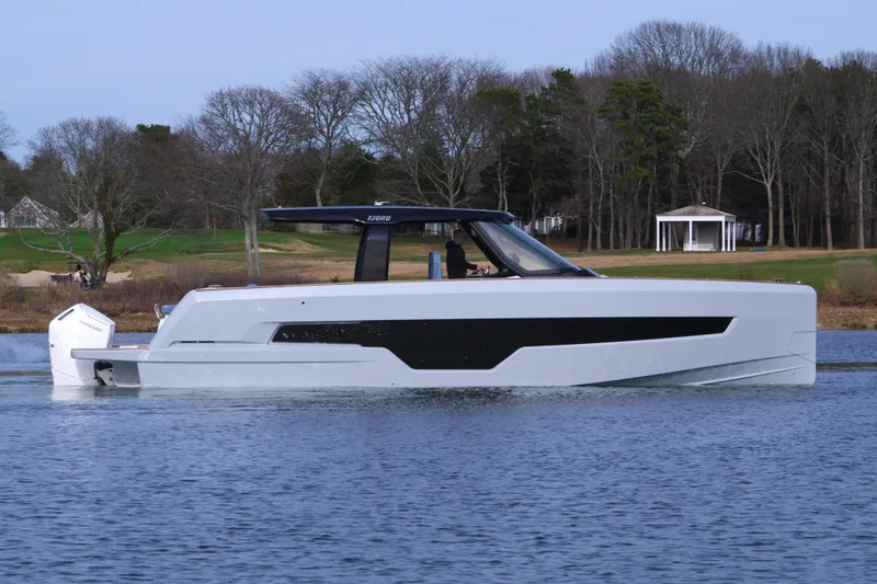 Slide: The Image of 2025 Fjord 41 XP boat on calm water, surrounded by trees and a small pavilion. - 2