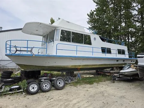 Slide: The Image of 1984 King's Craft Coastal Cruiser boat on land, surrounded by trees and trailers. - 0