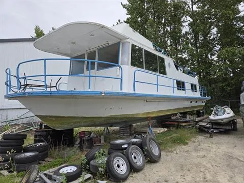 Slide: The Image of 1984 King's Craft Coastal Cruiser boat on land, surrounded by tires and trees. - 1