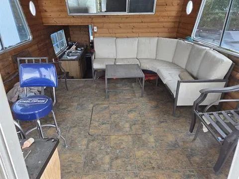 Slide: The Image of 1984 King's Craft Coastal Cruiser interior with beige sectional sofa, blue bar stool, and wood paneling. - 16