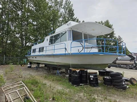 Slide: The Image of 1984 King's Craft Coastal Cruiser boat on land, surrounded by trees and tires. - 2