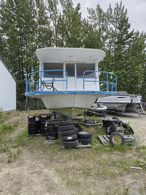 Slide: The Image of 1984 King's Craft Coastal Cruiser boat on land, surrounded by tires and trees. - 4