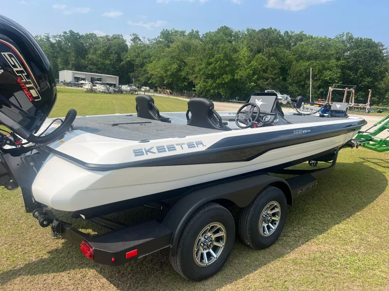Slide: The Image of 2025 Skeeter ZXR 21 boat on trailer, parked on grass, with trees in background. - 5