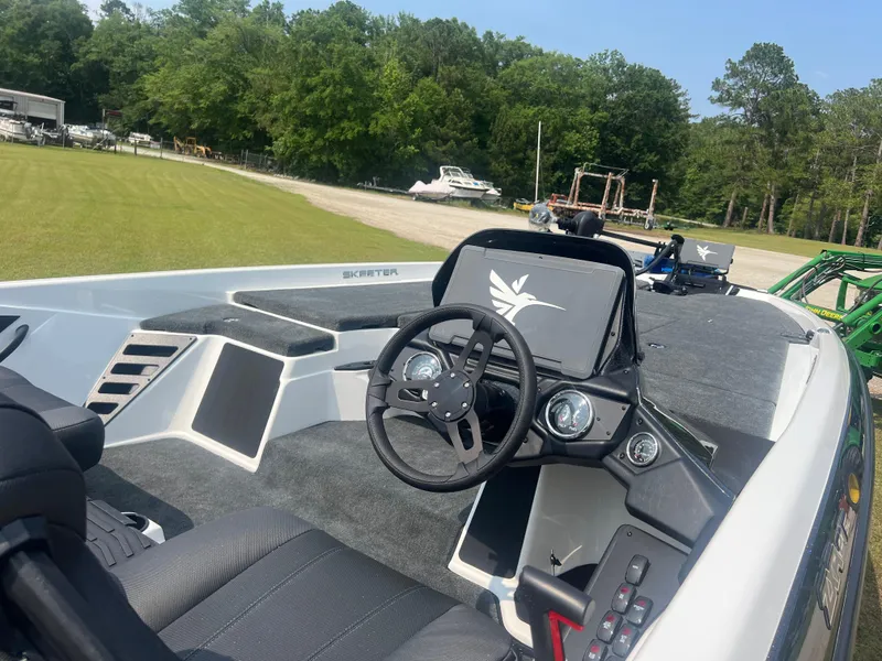 Slide: The Image of 2025 Skeeter ZXR 21 boat interior with steering wheel and dashboard, parked outdoors. - 7