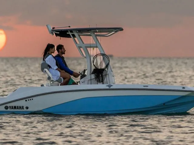 Slide: The Image of 2025 Yamaha Boats 195 FSH Sport cruising at sunset with two passengers. - 1