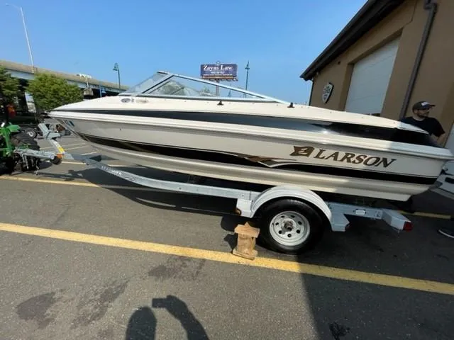 Slide: The Image of 2003 Larson 190LXi boat on trailer, parked outdoors near a building. - 1