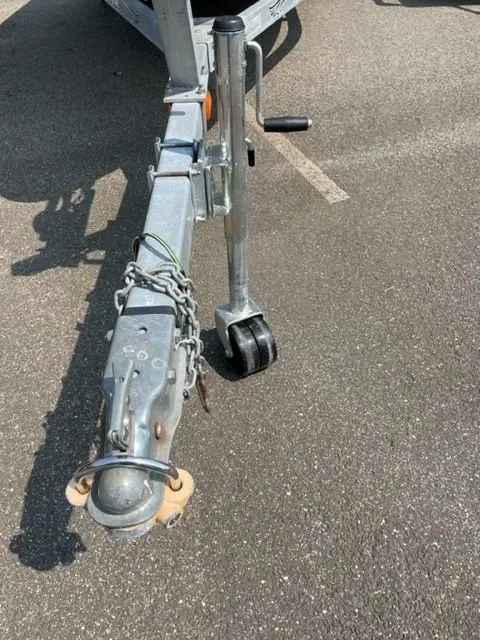 Slide: The Image of Trailer hitch of a 2003 Larson 190LXi boat on asphalt surface. - 10