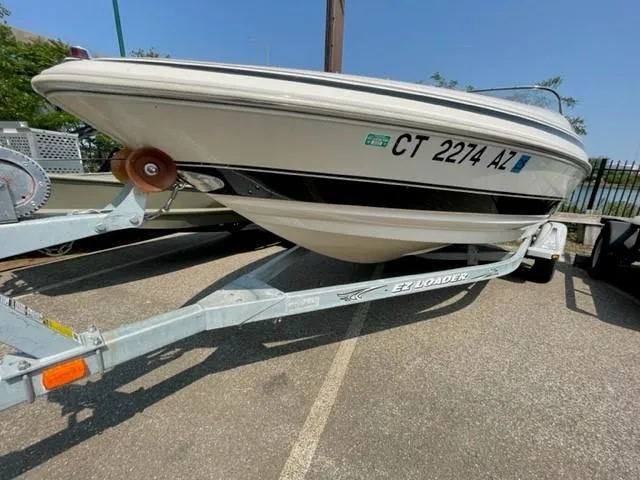 Slide: The Image of 2003 Larson 190LXi boat on trailer, parked outdoors, with visible registration number. - 2