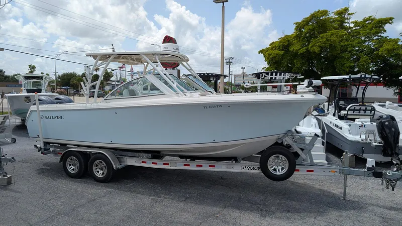 The Image of 2016 Sailfish 275 DC boat on trailer, parked outdoors under cloudy sky. - 0