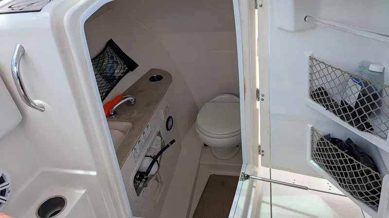 Slide: The Image of 2016 Sailfish 275 DC boat interior with compact bathroom and storage. - 10