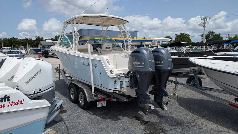 Slide: The Image of 2016 Sailfish 275 DC boat with dual Yamaha engines on a trailer in a marina. - 2