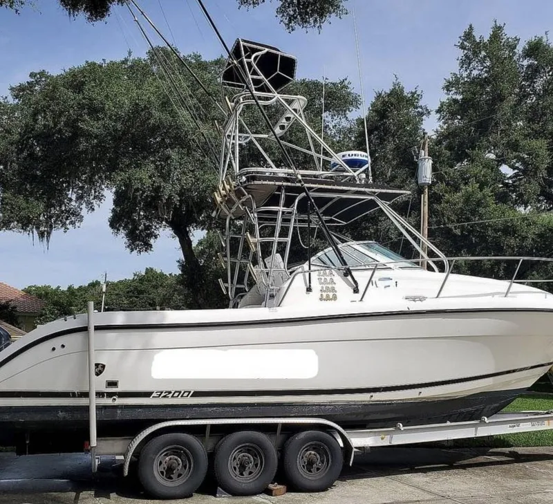 Slide: The Image of 2000 Century 3200 WA boat on trailer, parked outdoors with trees in background. - 1