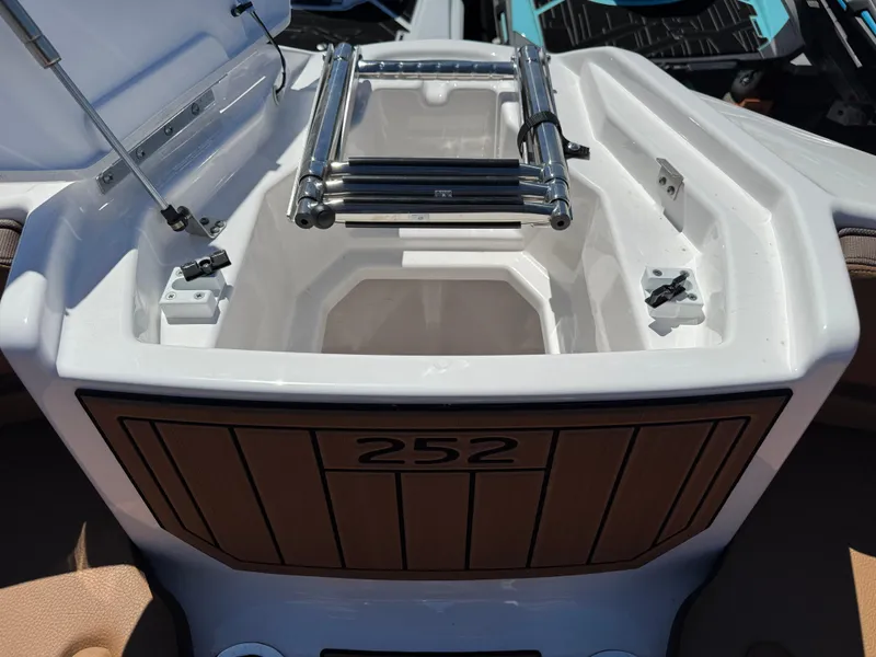 Slide: The Image of 2025 Yamaha Boats 252S storage compartment with ladder, open lid, and sleek design. - 26