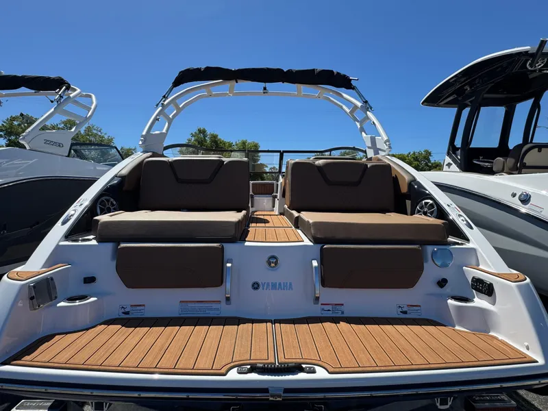 Slide: The Image of 2025 Yamaha Boats 252S with spacious seating and sleek design, docked under clear blue sky. - 2