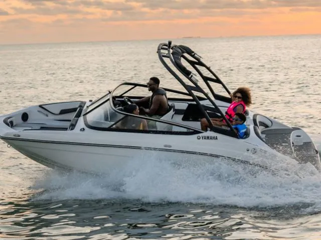 Slide: The Image of 2025 Yamaha Boats SX195 cruising on water at sunset with passengers. - 2