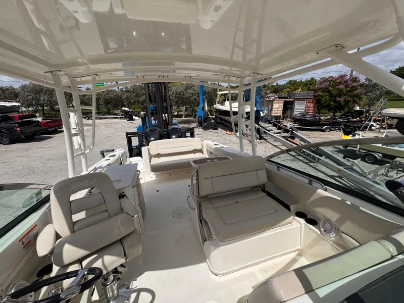 Slide: The Image of 2014 Boston Whaler 270 Vantage boat interior with seating and steering wheel, docked outdoors. - 16