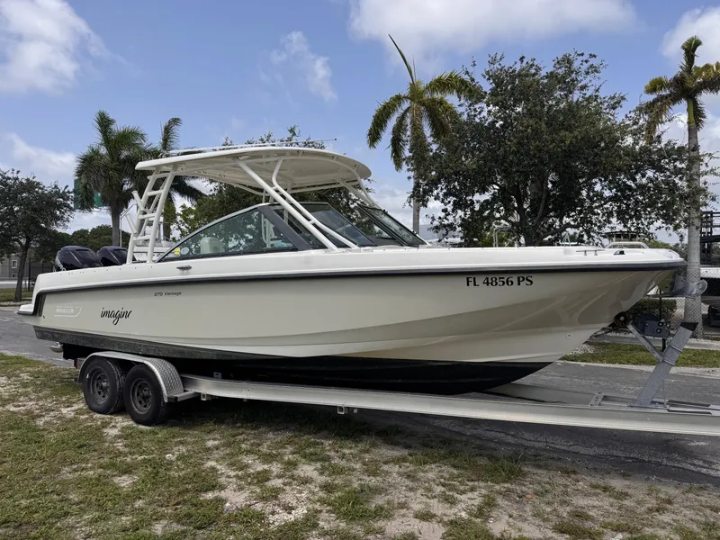 Slide: The Image of 2014 Boston Whaler 270 Vantage boat on trailer, parked outdoors with palm trees. - 21