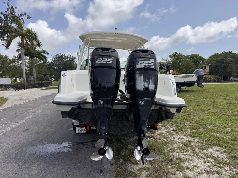 Slide: The Image of 2014 Boston Whaler 270 Vantage with twin 225 horsepower engines, parked on a grassy area. - 23