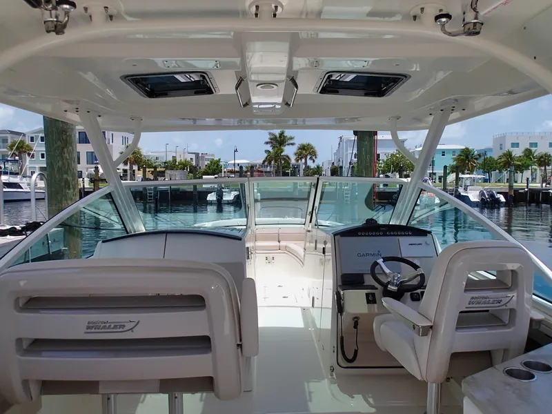 Slide: The Image of 2017 Boston Whaler 320 Vantage boat interior with helm and seating at marina. - 11