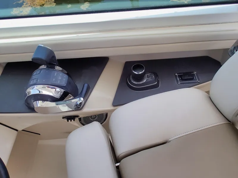 Slide: The Image of 2017 Boston Whaler 320 Vantage helm controls with beige seating and modern dashboard. - 12