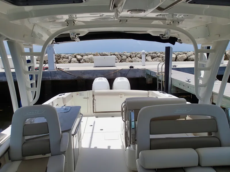 Slide: The Image of 2017 Boston Whaler 320 Vantage boat interior at dock, featuring seating and dual engines. - 5