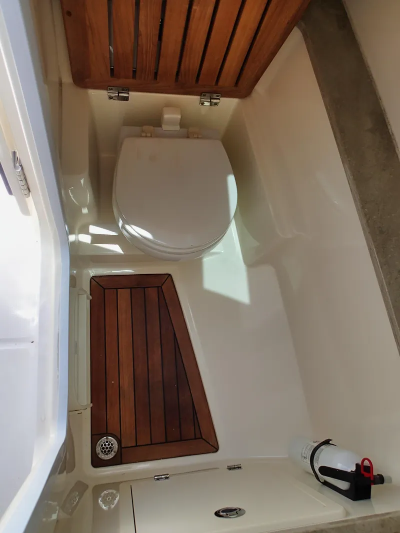 Slide: The Image of 2017 Boston Whaler 320 Vantage boat interior with wooden accents and toilet. - 7
