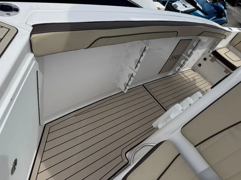 Slide: The Image of 2025 Yamaha Boats 255 FSH Sport H interior with beige seating and wood-style flooring. - 17