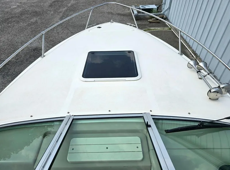 Slide: The Image of 1994 Sea Ray 220 Overnighter boat deck with hatch and railing, docked near a building. - 11