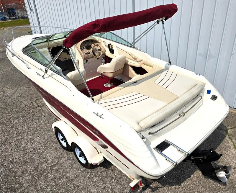 Slide: The Image of 1994 Sea Ray 220 Overnighter boat with red canopy and dual-axle trailer, parked outdoors. - 2
