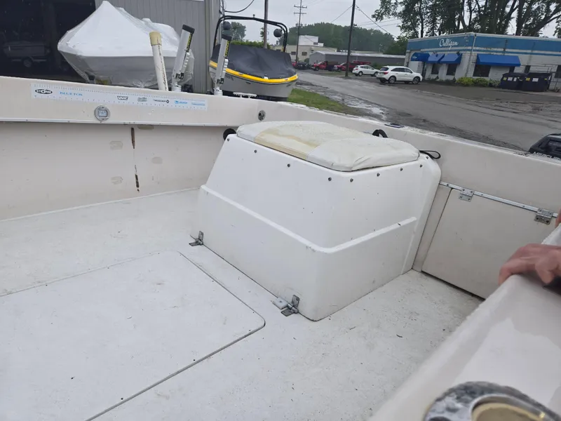 Slide: The Image of 1992 Dixie 21 boat interior with seating and storage, parked near a dealership. - 7