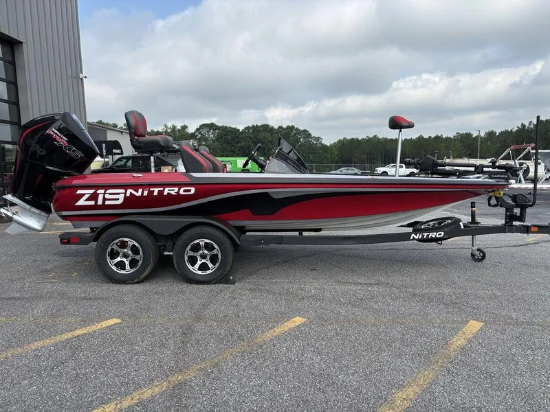 The Image of 2025 Nitro Z19 Pro boat on trailer, red and black design, parked outdoors. - 1