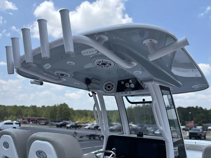 Slide: The Image of 2025 Sportsman OPEN 262 boat with rod holders and speakers under a clear sky. - 22