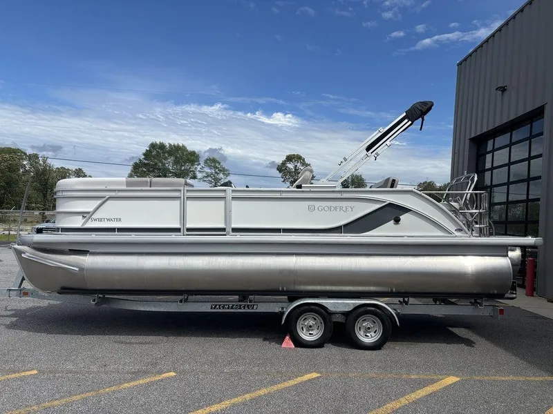 The Image of 2025 Godfrey SWEETWATER 2286 SFL pontoon boat on trailer, parked outdoors. - 1