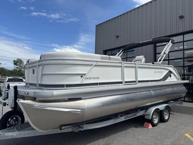 Slide: The Image of 2025 Godfrey SWEETWATER 2286 SFL pontoon boat on trailer, parked outside a building. - 3