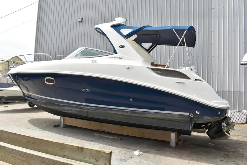 The Image of 2011 Sea Ray 310 Sundancer boat with blue hull and white top, docked outdoors. - 0