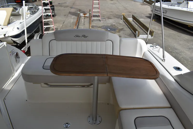 Slide: The Image of 2011 Sea Ray 310 Sundancer cockpit with wooden table and cushioned seating. - 13