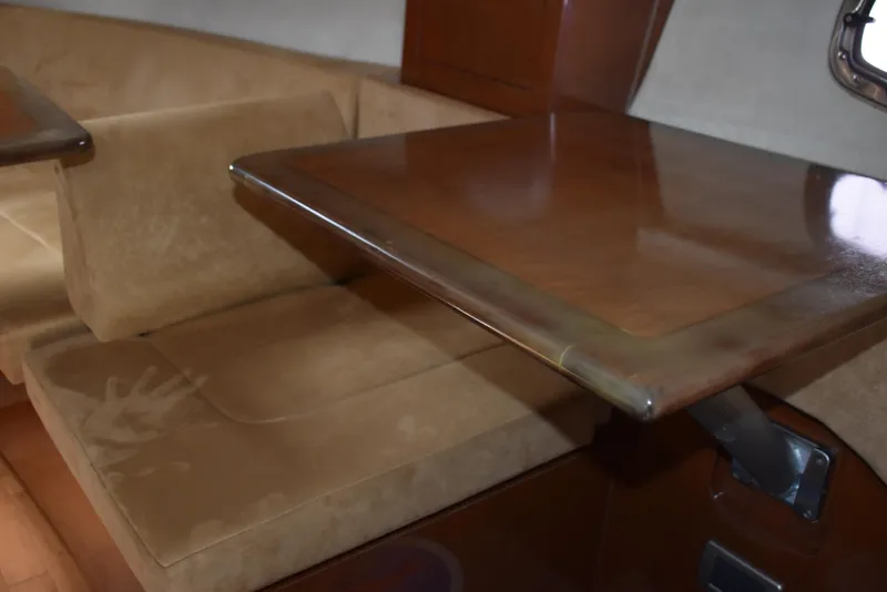 Slide: The Image of Interior of 2011 Sea Ray 310 Sundancer with wooden table and beige seating. - 38