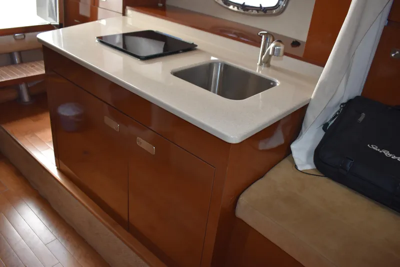 Slide: The Image of 2011 Sea Ray 310 Sundancer interior with kitchenette, sink, and wooden cabinetry. - 45